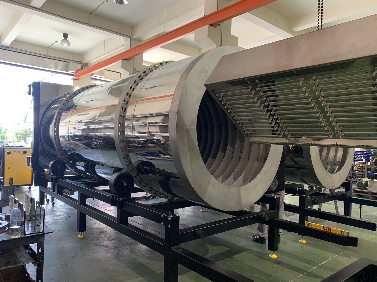 Industrial infrared rotary dryer for plastics processing, featuring a cylindrical design with internal heating elements and a reflective exterior on a support frame.