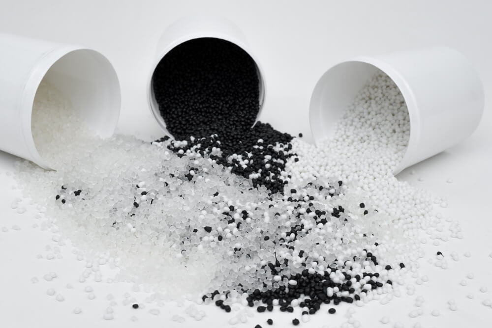 Blending of black and white thermoplastic elastomer granules on a white background.
