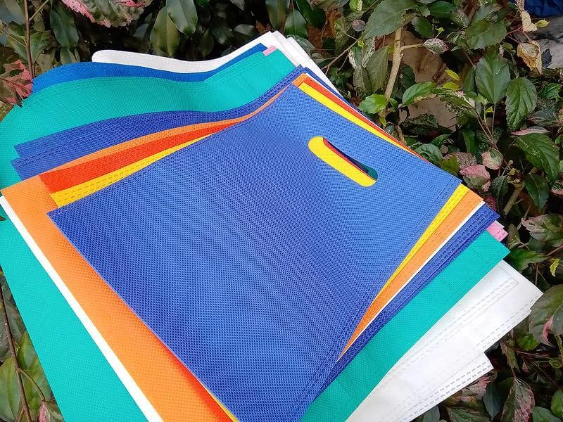 colorful eco friendly non woven bags on green plant