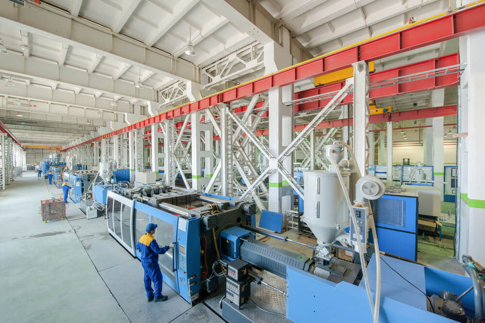 A worker investigating the mold temperature of injection molding press machines.